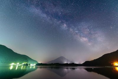 Scenic view of lake and mountains against sky at night