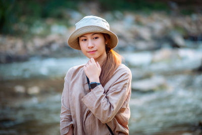 Portrait of beautiful young woman standing against water