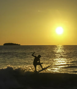 Silhouette man on beach against sky during sunset