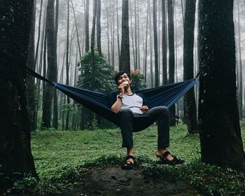 Portrait of young woman sitting on hammock in forest