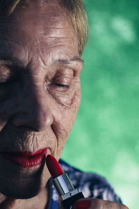Old woman in the foreground wearing red lipstick on a green background