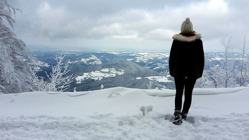 Man standing on snow covered mountain against sky