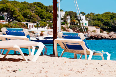 Deck chairs on beach against sky