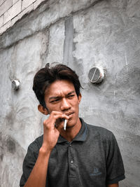 Portrait of young man standing against wall