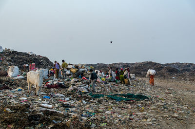 Group of people on garbage against the sky