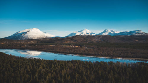 View of the wooded area and malselva river with a reflection on snow-covered hills. finnmark region