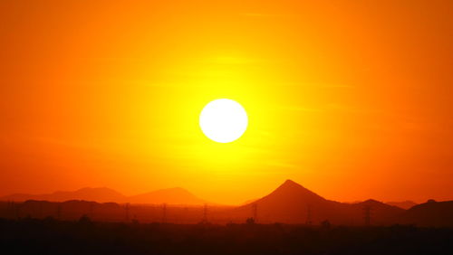 Scenic view of silhouette mountains against orange sky