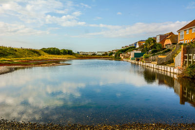 Scenic view of lake by buildings against sky