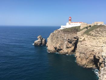 Scenic view of cliff by sea against clear sky