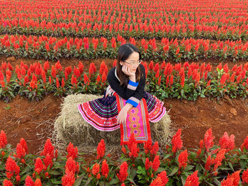 Rear view of woman standing amidst yellow flowering plants on field