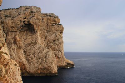 Rock formations by sea against sky