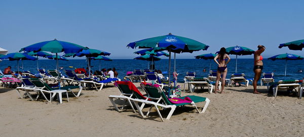 Deck chairs on beach against sky