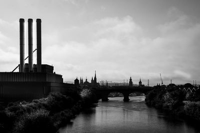 Bridge over river against sky in city