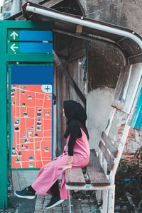 Woman sitting on bench at bus stop