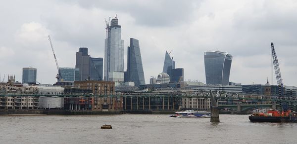 Modern buildings by river against sky in city