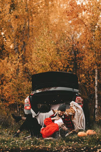 A romantic couple in love in warm sweaters is walking traveling by car in the autumn forest in fall