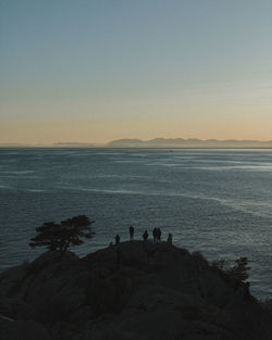 People on beach against sky during sunset