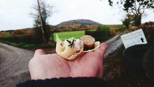 Close-up of man holding ice cream against trees