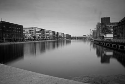 Buildings by river against sky in city