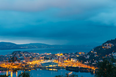 High angle view of illuminated city by sea against sky