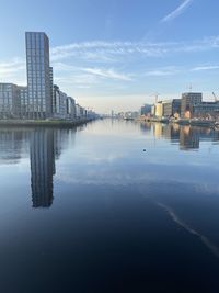 Buildings by river against sky in city