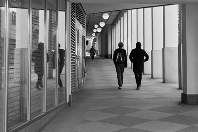 Rear view of people walking in corridor of building
