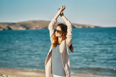 Woman standing at beach against sky