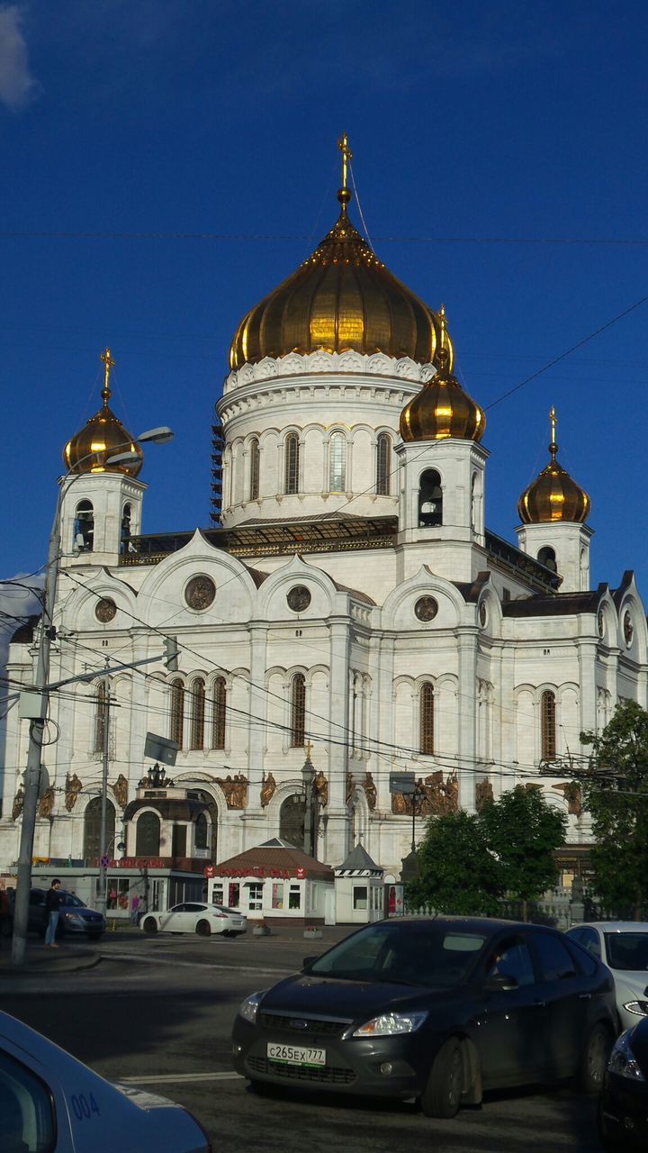 building exterior, church, architecture, religion, place of worship, built structure, spirituality, cathedral, blue, low angle view, car, dome, transportation, clear sky, sky, land vehicle, mode of transport, travel