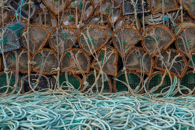 Ropes by stacked rusty lobster traps at harbor