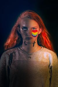 Portrait of teenage girl with face paint standing over black background