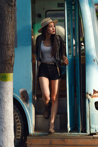 Full length of young woman standing in bus