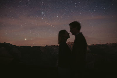 Silhouette friends standing against sky at night