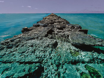 Rock formation on sea shore against sky