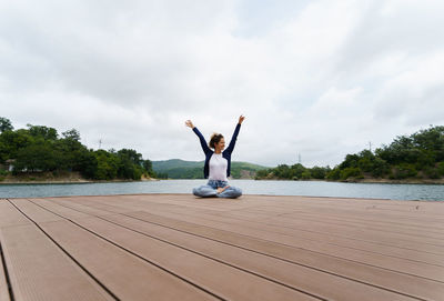 Woman with arms raised against sky