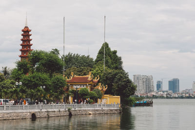 Temple by lake against sky