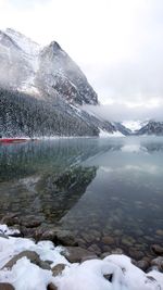 Scenic view of frozen lake by snowcapped mountain against sky