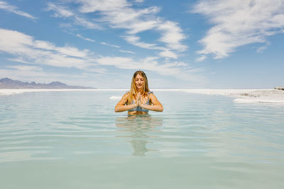 Young woman meditating in water in bonneville salt flats.