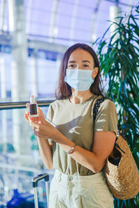 Portrait of woman wearing mask standing at airport