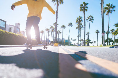 Man skateboarding on road against sky