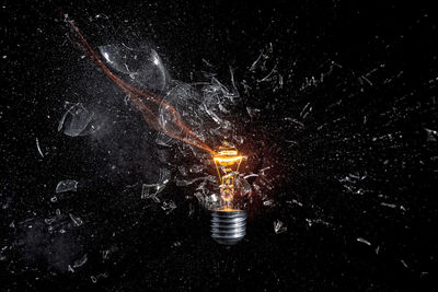 Close-up of illuminated light bulb against black background