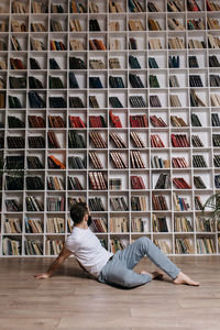 A brutal man sitting on the floor among books and bookshelves in the library