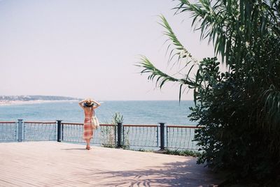 Woman standing by sea against clear sky