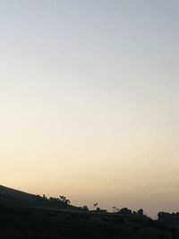 Scenic view of silhouette field against clear sky during sunset