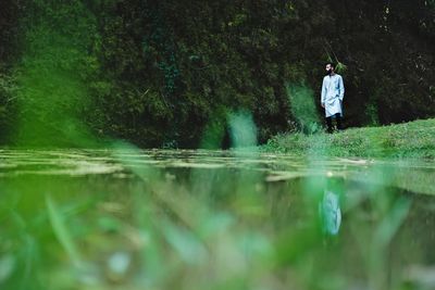 Rear view of man standing by lake