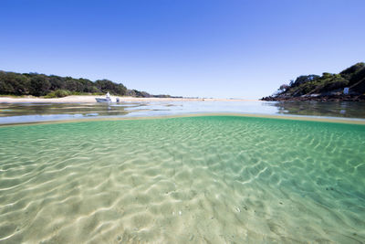 Scenic view of beach against clear blue sky