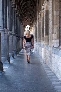 Full length rear view of woman walking on footpath