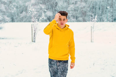 Portrait of young man standing on snow covered field