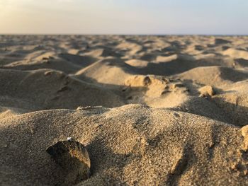 Scenic view of sand dunes at beach against sky