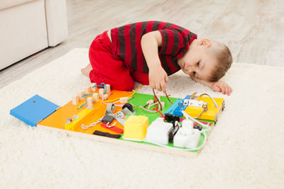 High angle view of boy playing with toy on floor at home