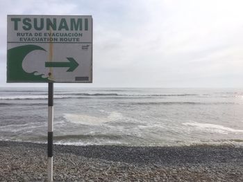 Information sign on beach against sky